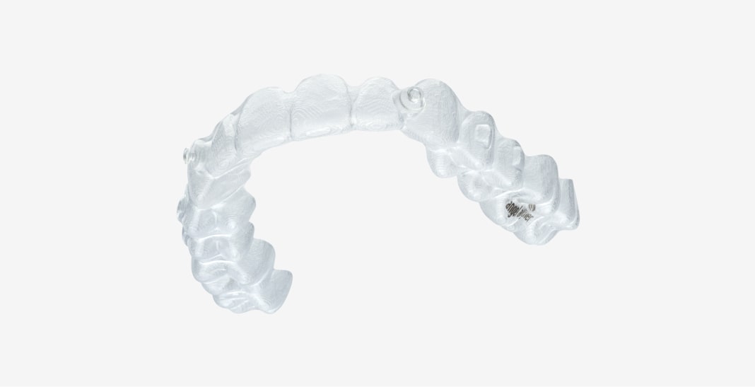 Content (6)-min A clear, curved dental aligner is shown on a plain white background, designed to fit over teeth for orthodontic adjustment.